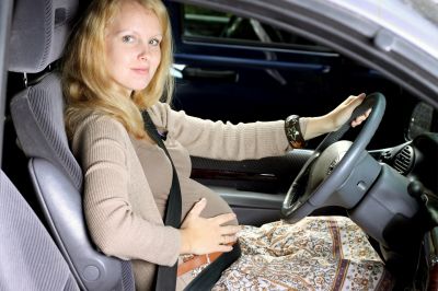 Kobieta w ciąży prowadząca samochód z zapiętymi pasami