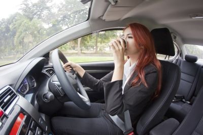 Kobieta prowadząca samochód i pijąca kawę