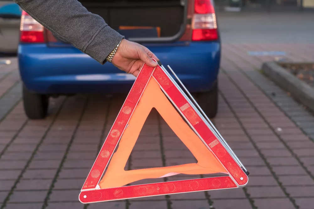 Trojkat ostrzegawczy ustawiony za unieruchomionym samochodem na poboczu