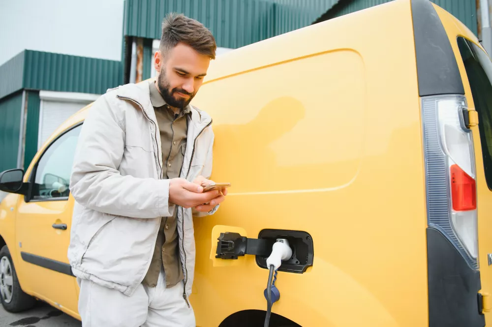 happy-young-adult-man-charging-automobile-battery-from-small-public-station