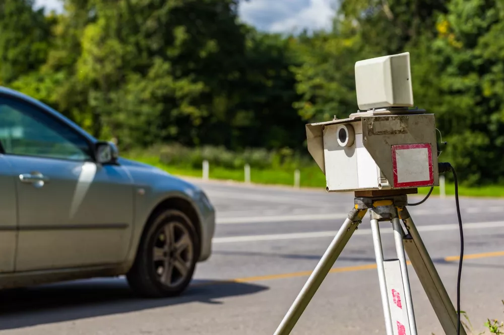 Mobile speed camera on a tripod by the road with a passing car