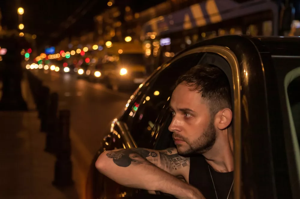 Young man at the wheel of a car at night on a city street