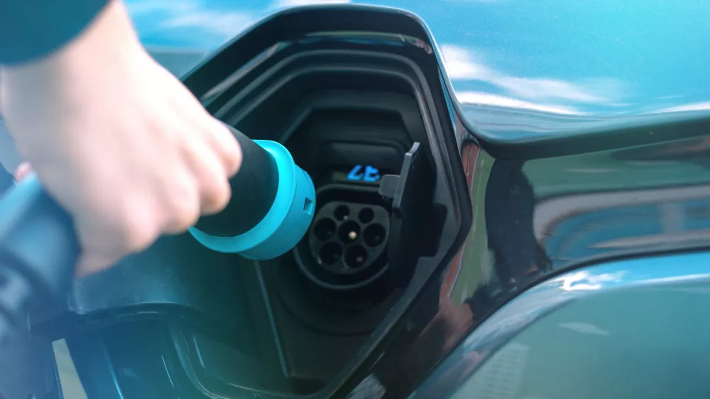 man-plugging-charger-into-electric-car-charge-station